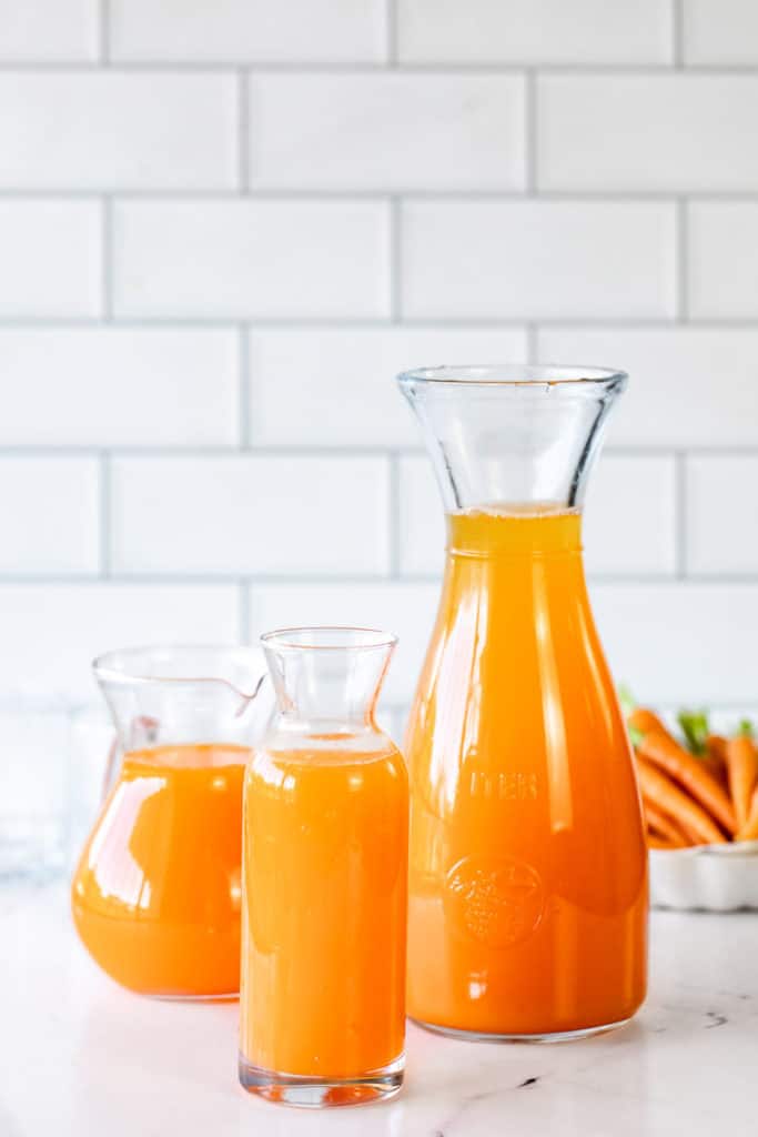 orange juice in different glass pitchers on white background
