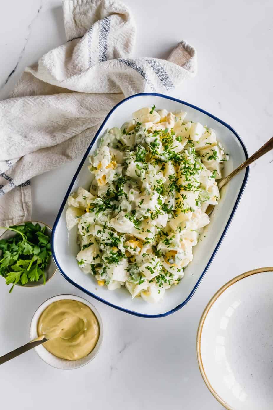 A side of potato salad with fresh herbs and mustard.