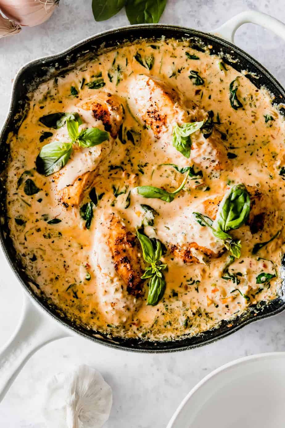 A creamy sauce in a skillet with fresh herbs.