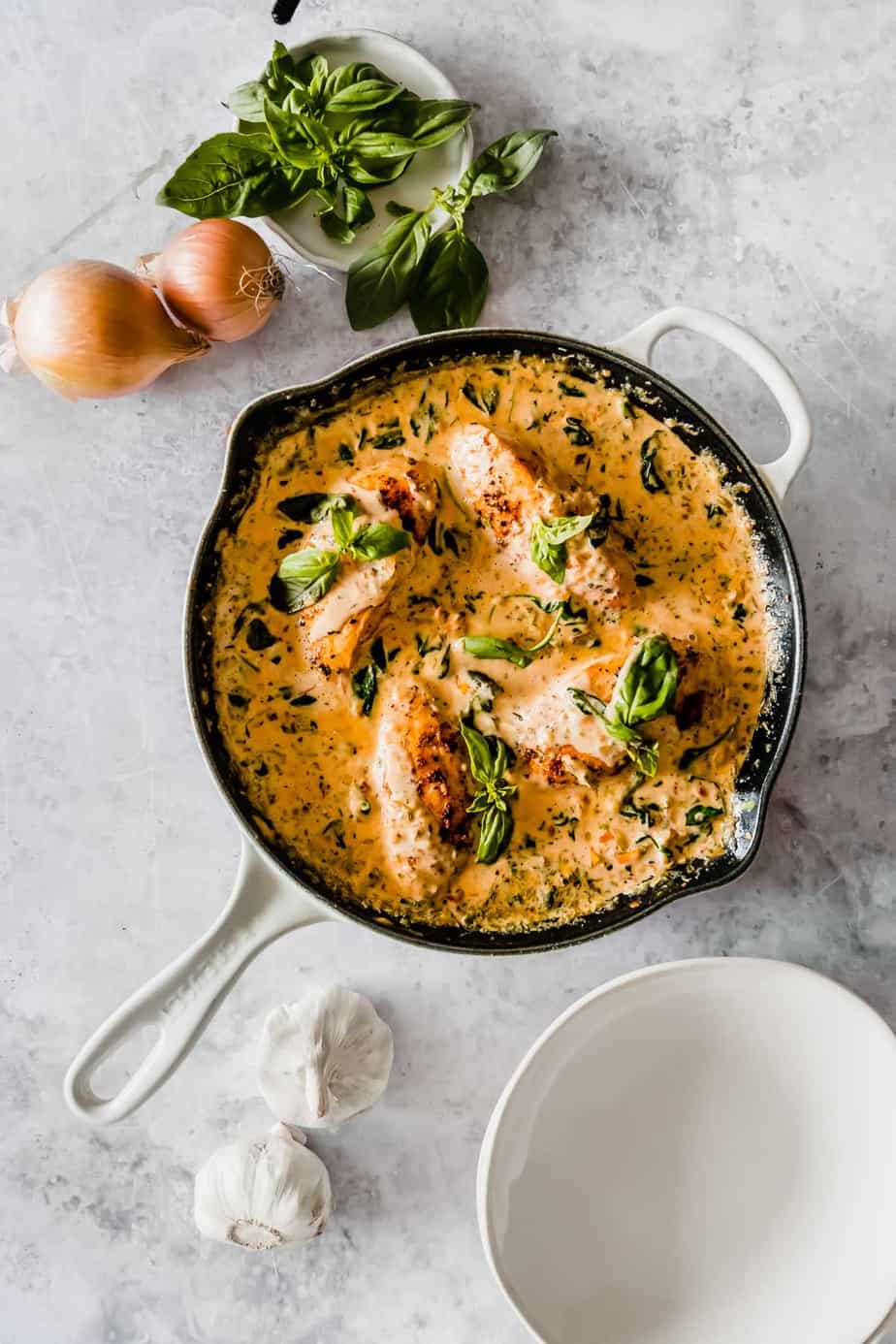 A skillet with creamy sauce and chicken breasts.