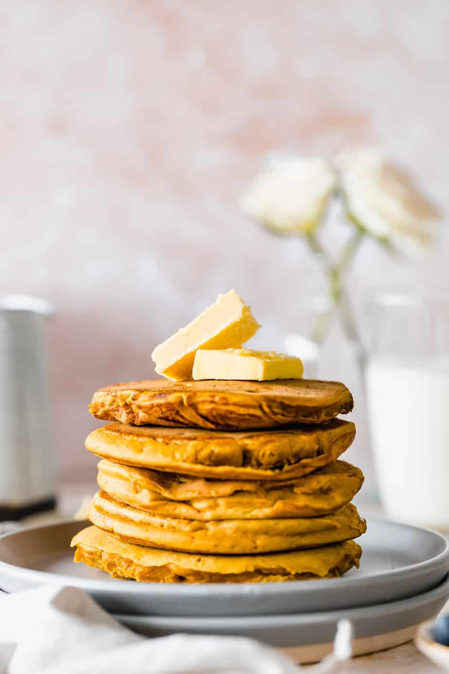 A stack of pumpkin pancakes with vegan butter on top.