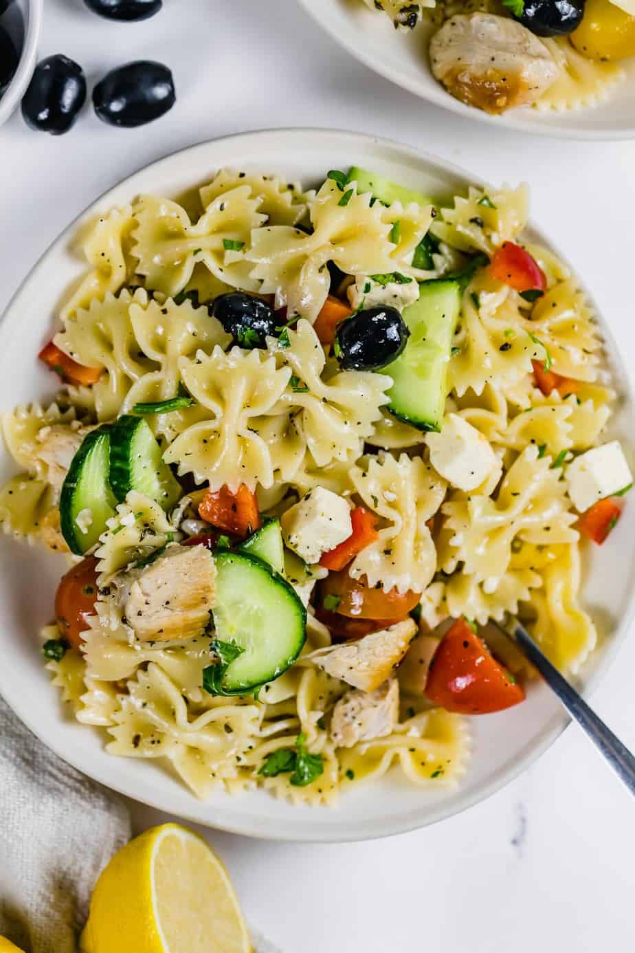 A pasta salad in a white bowl to serve as a BBQ chicken side dish.