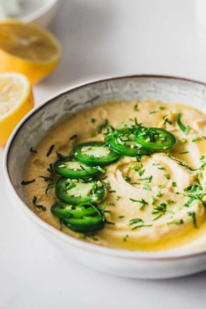 jalapeno hummus in grey bowl with sliced jalapenos