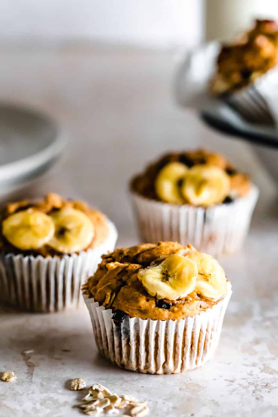 Pumpkin Banana Oatmeal Muffins in paper liners topped with banana and oatmeal