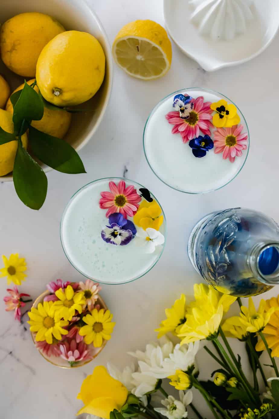 Blueberry gin sours in serving glasses topped with fresh flowers.
