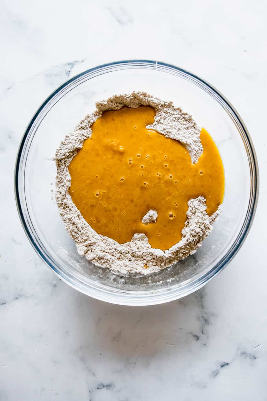 Combining wet and dry ingredients in a glass bowl.