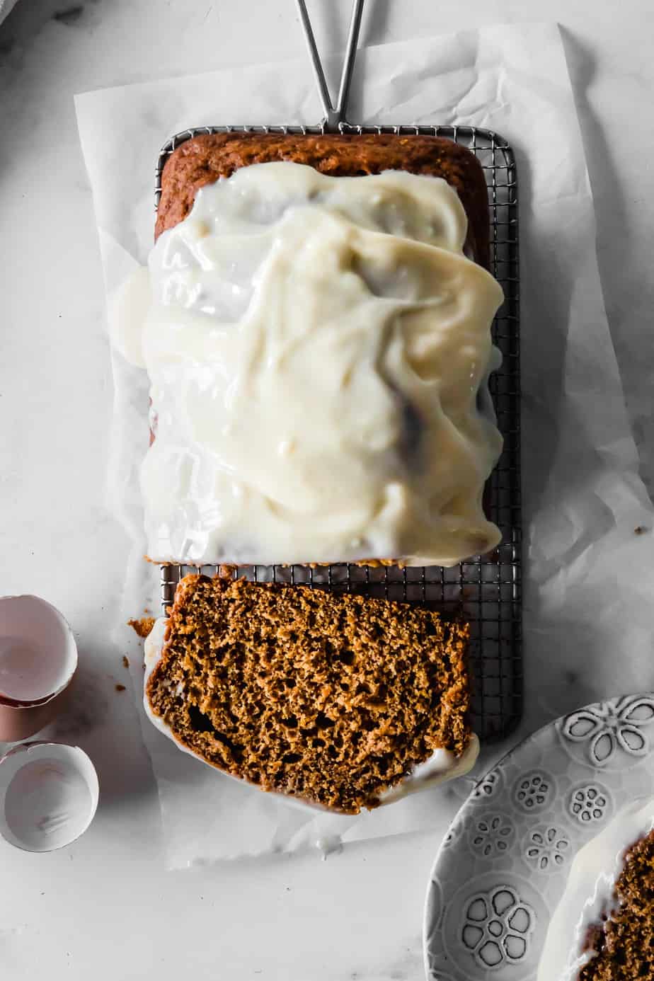 Pumpkin Bread with Cream Cheese Glaze on a cooling rack and baking paper.