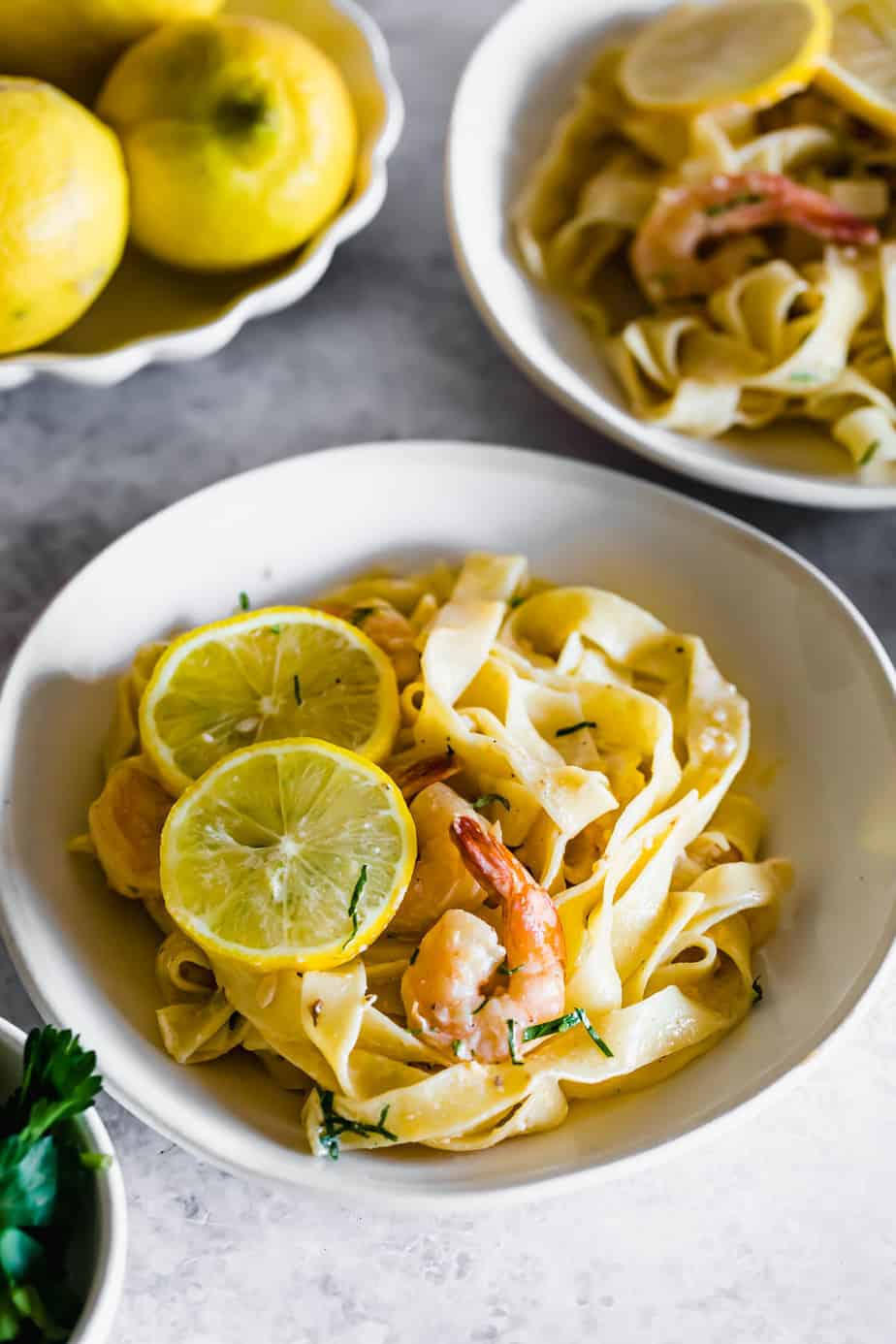 Creamy shrimp pasta served in a white bowl with fresh lemon slices and parsley.