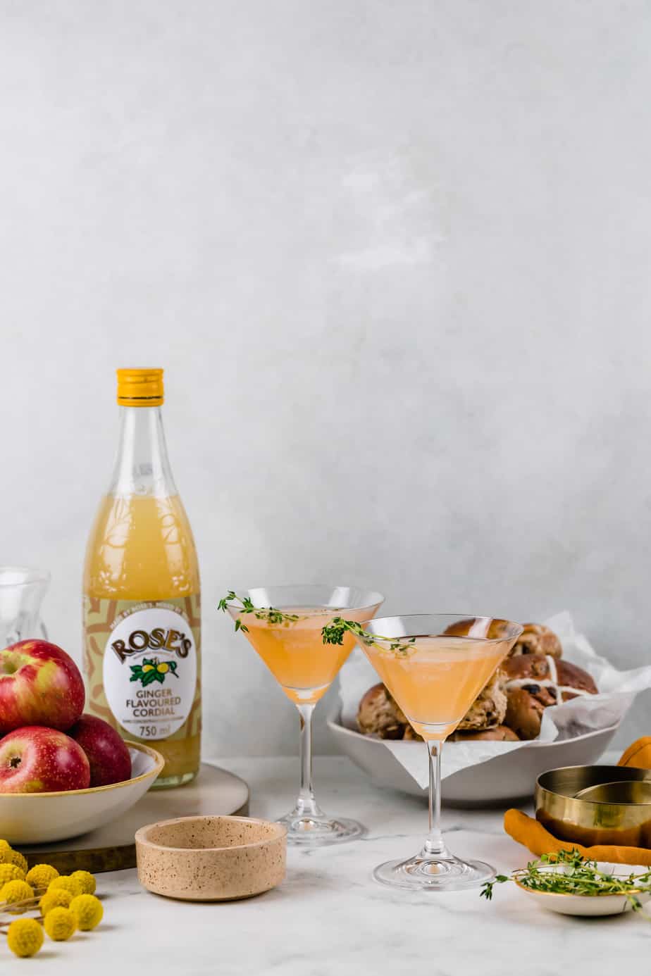 Two spiced apple cocktails in stemmed glasses with a  grey background.