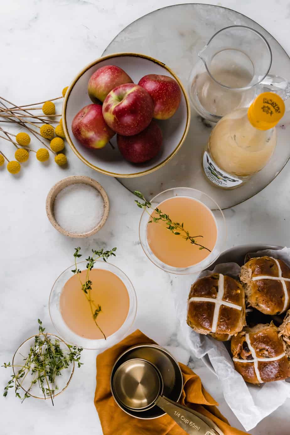 Glasses of spicy apple cocktails with fresh thyme and apples around them.