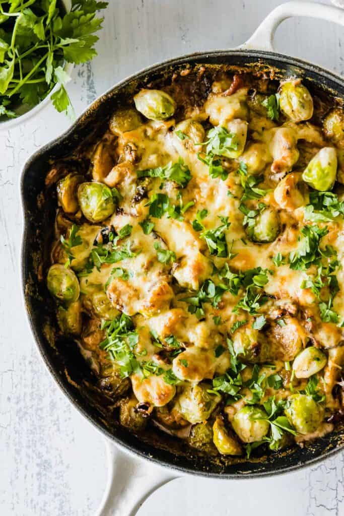 Cheesy Brussels Sprouts with Bacon is an easy side dish that will leave everyone wanting more! Crisp sauteed brussels sprouts and smoky bacon are oven-baked in a creamy garlic sauce topped with parmesan and mozzarella cheese. (keto-friendly and gluten-free)