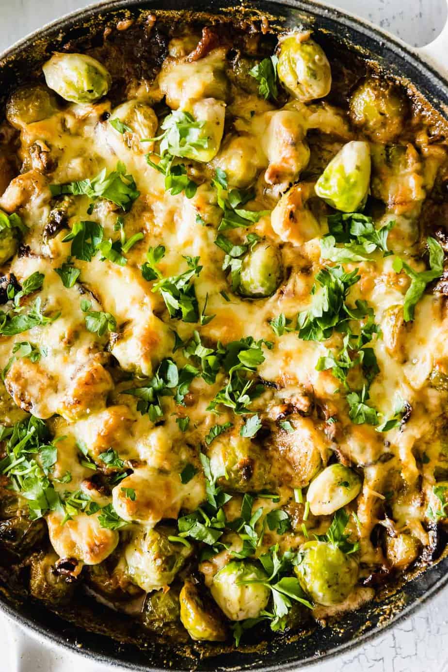 Cheesy brussels sprouts in a black skillet.