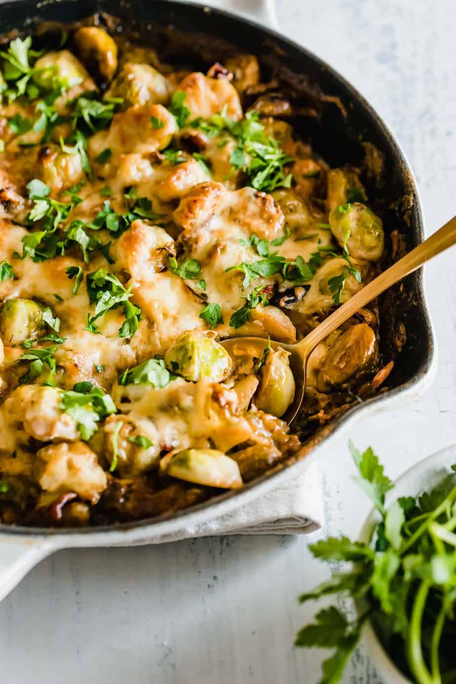 Cheesy Brussels Sprouts with Bacon is an easy side dish that will leave everyone wanting more! Crisp sauteed brussels sprouts and smoky bacon are oven-baked in a creamy garlic sauce topped with cheese.