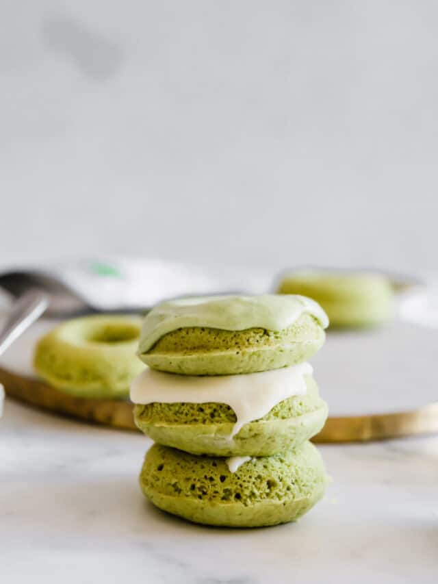 A stack of matcha donuts with cream cheese glaze.