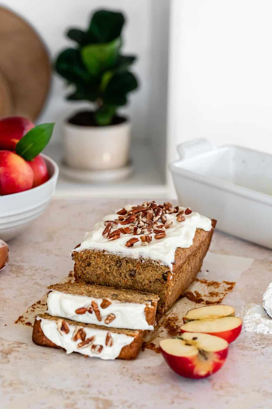 A carrot and apple loaf with frosting and chopped nuts.
