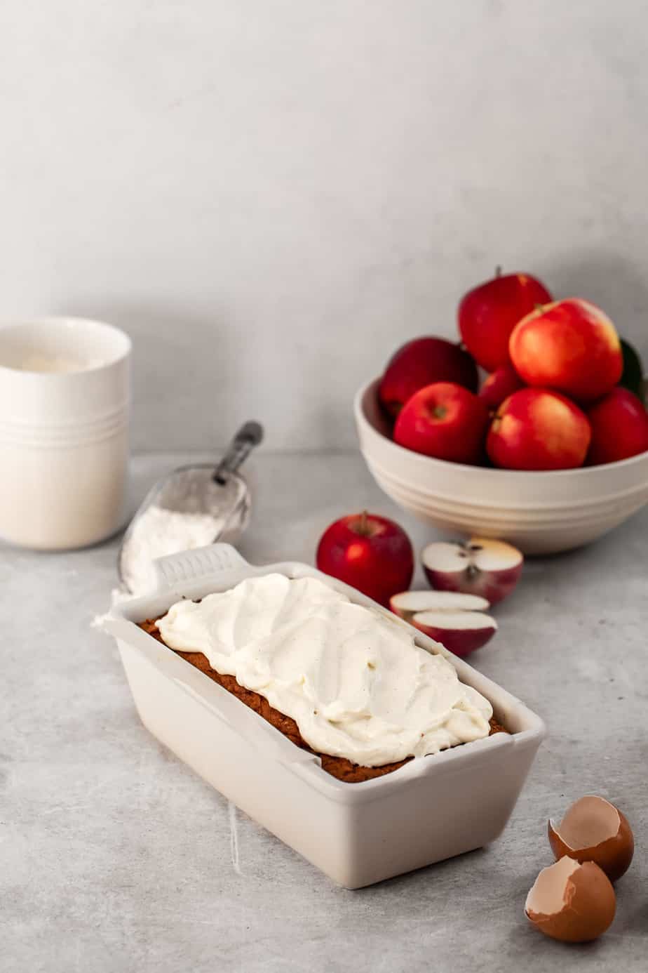 A loaf in a white tin with red apples.