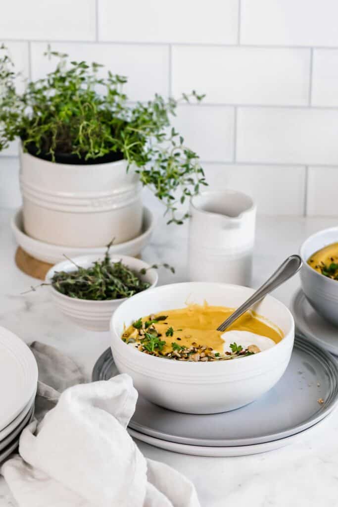 A bowl of yellow soup topped with fresh herbs and a dollop of yogurt.