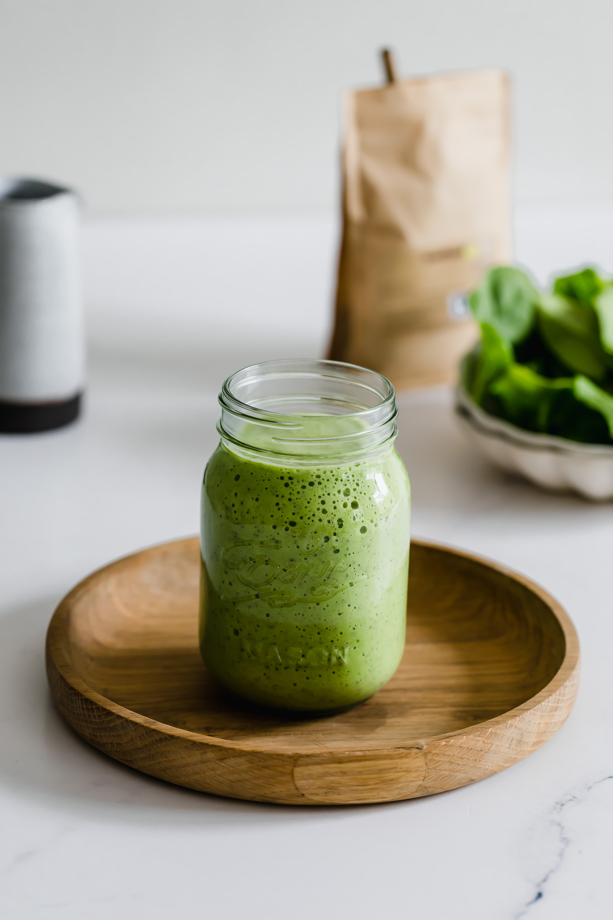 pineapple spinach smoothie in a mason jar with white straw