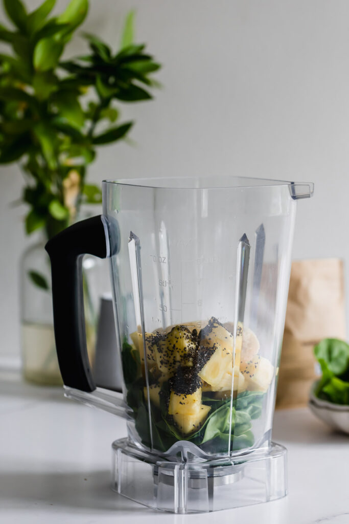 pineapple spinach smoothie in a mason jar with white straw