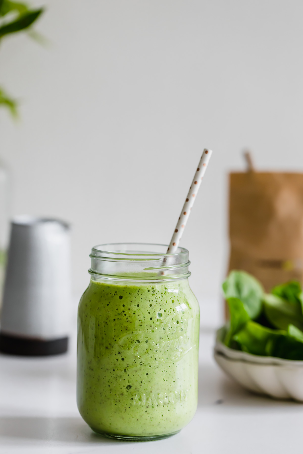 pineapple spinach smoothie in a mason jar with white straw