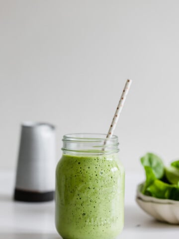 pineapple spinach smoothie in a mason jar with white straw