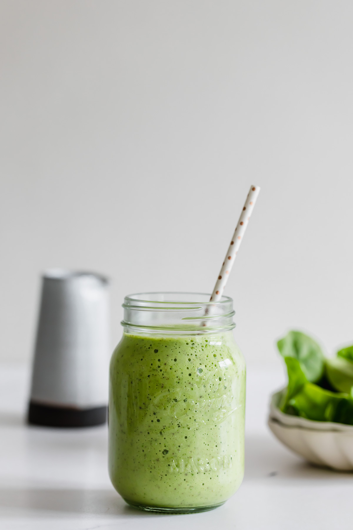 pineapple spinach smoothie in a mason jar with white straw