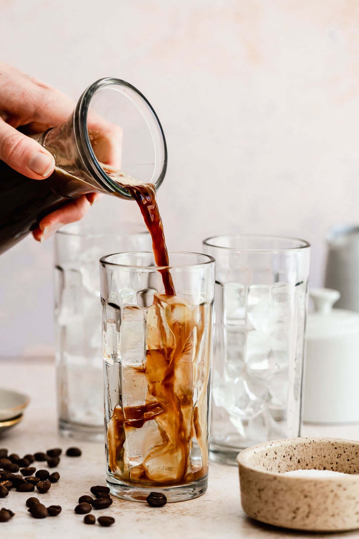 Espresso pouring into glasses filled with ice cubes
