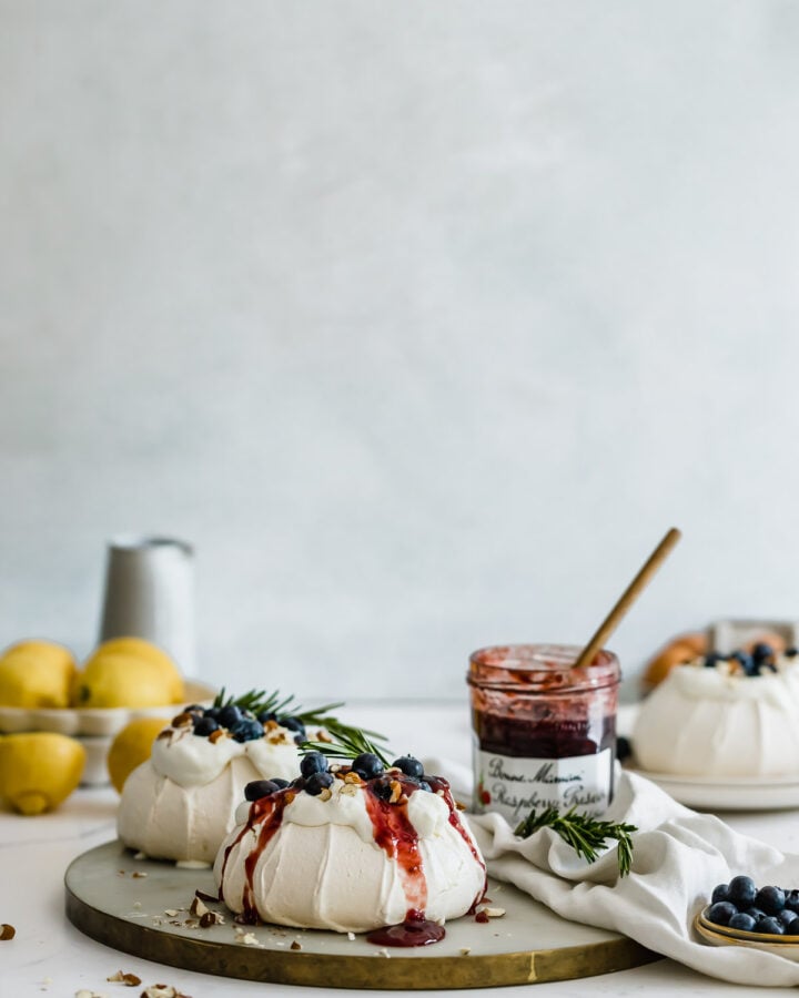 Pavlova with fresh berries and jam on marble board