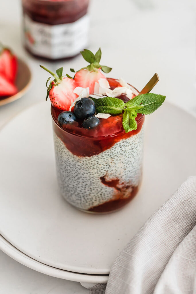 white plates with chia pudding in glass and strawberry jam 