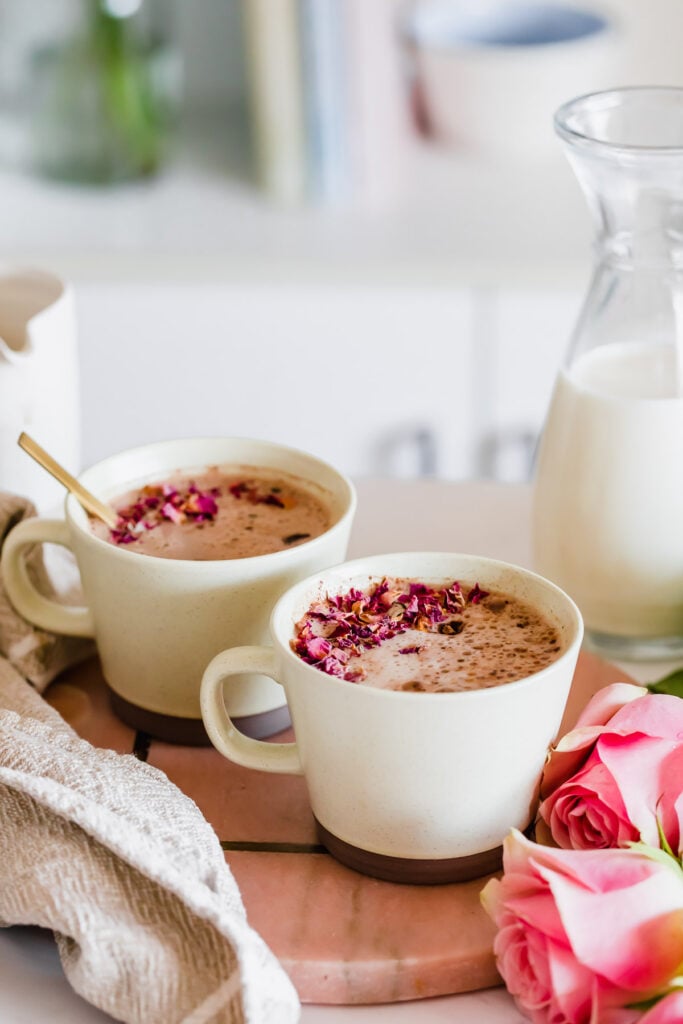 Maca latte in brown mug with dried rose petals on the foam
