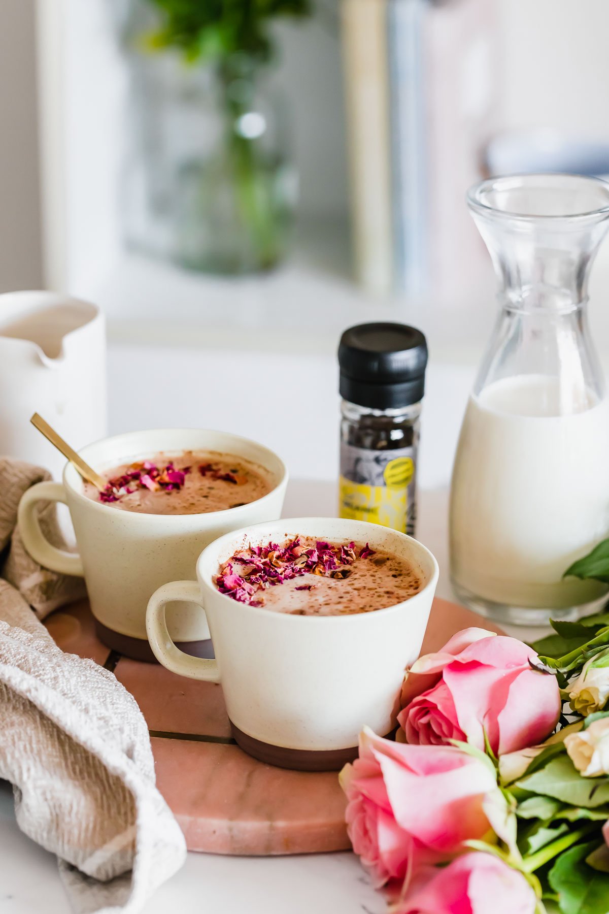 Maca latte in brown mug on pink marble with peppercorns and milk