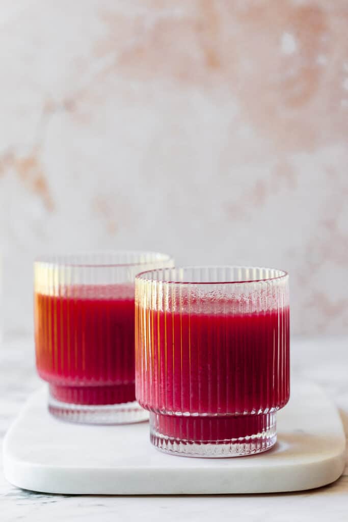 two glasses with carrot and beetroot juice on marble