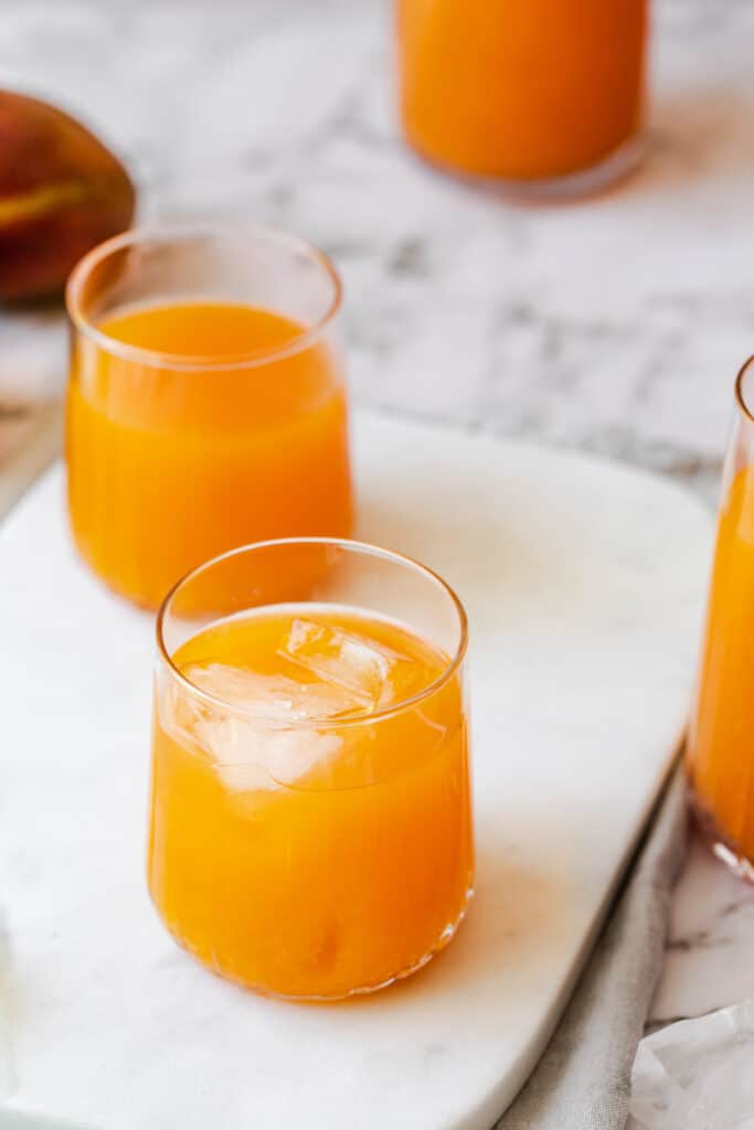 carrot mango juice in glasses on marble
