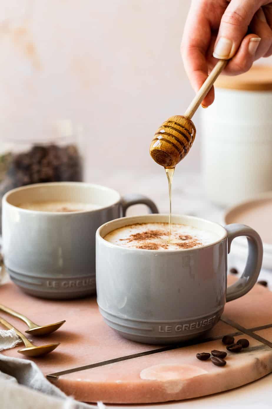 grey mug on pink marble with honey drizzle on top of creamer froth.