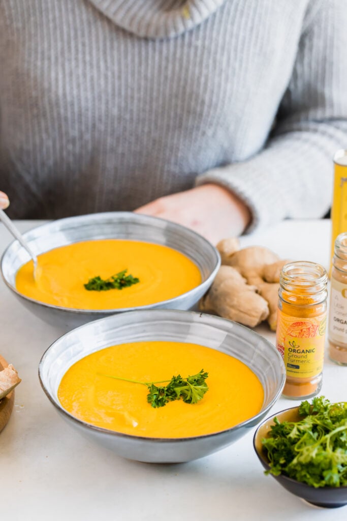 roast carrot and butternut soup in blue bowl with grey background