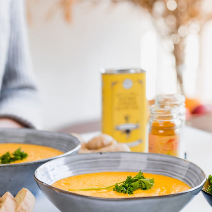 carrot and butternut soup in blue bowl with oil in background