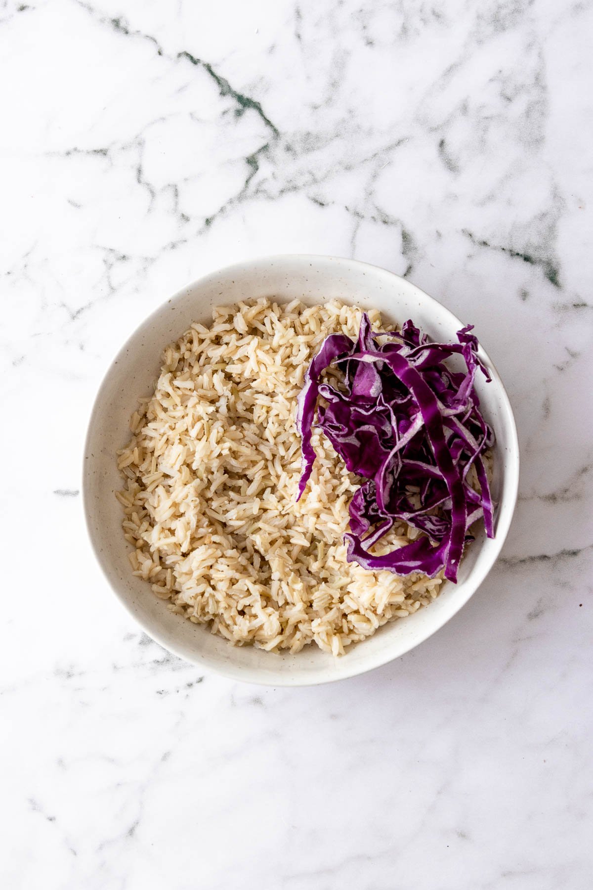 White bowl filled with rice and shredded cabbage