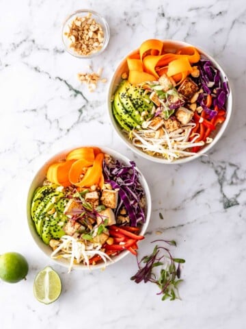 two white bowls with avocado, carrots and cabbage. dragon bowls with fresh limes