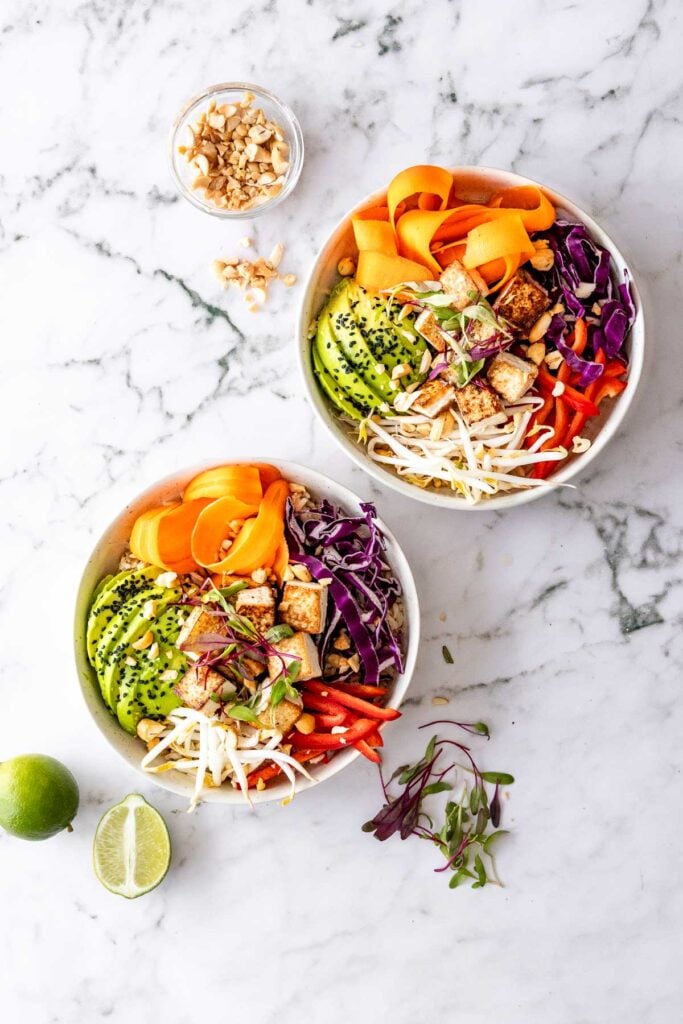 two white bowls with avocado, carrots and cabbage. dragon bowls with fresh limes