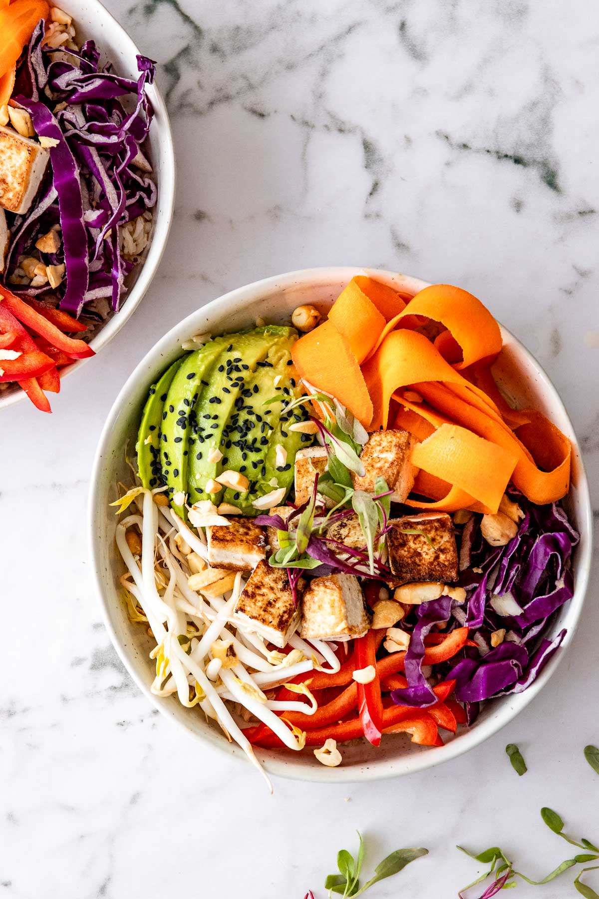white bowl filled with rice, avocado, carrots and bean sprouts