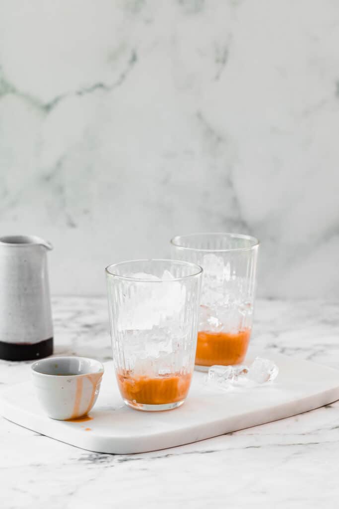 glass with caramel syrup and ice cubes on marble