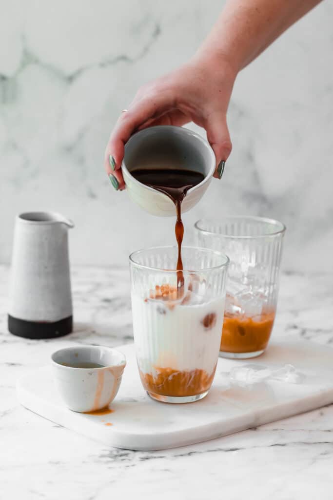 milk in glass with caramel syrup and coffee on marble