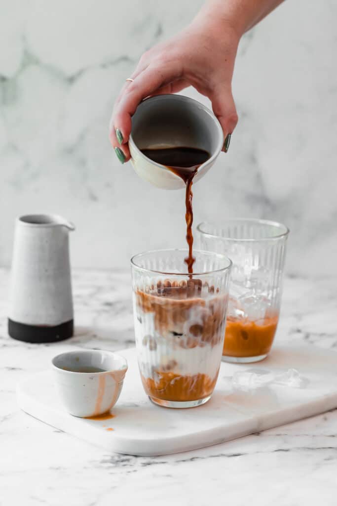 coffee pouring into caramel iced latte with small jug