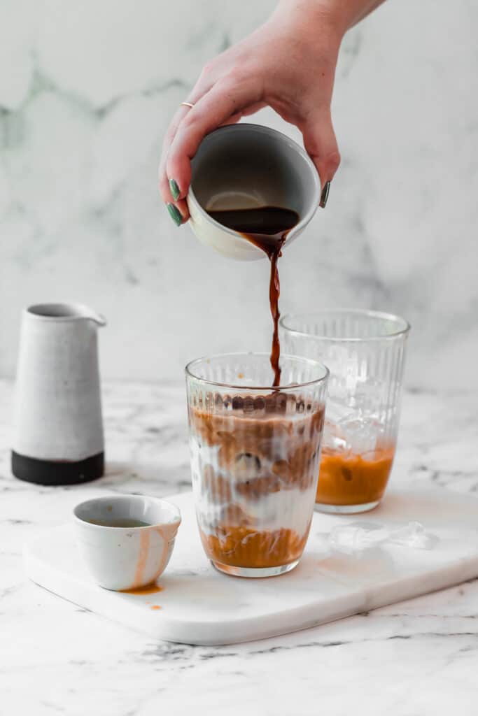 coffee poured into caramel iced latte on marble board