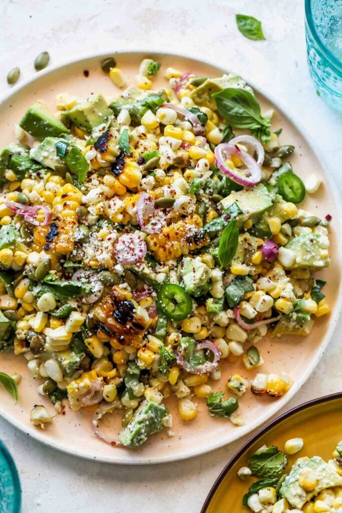 corn salad on white plate with blue glasses