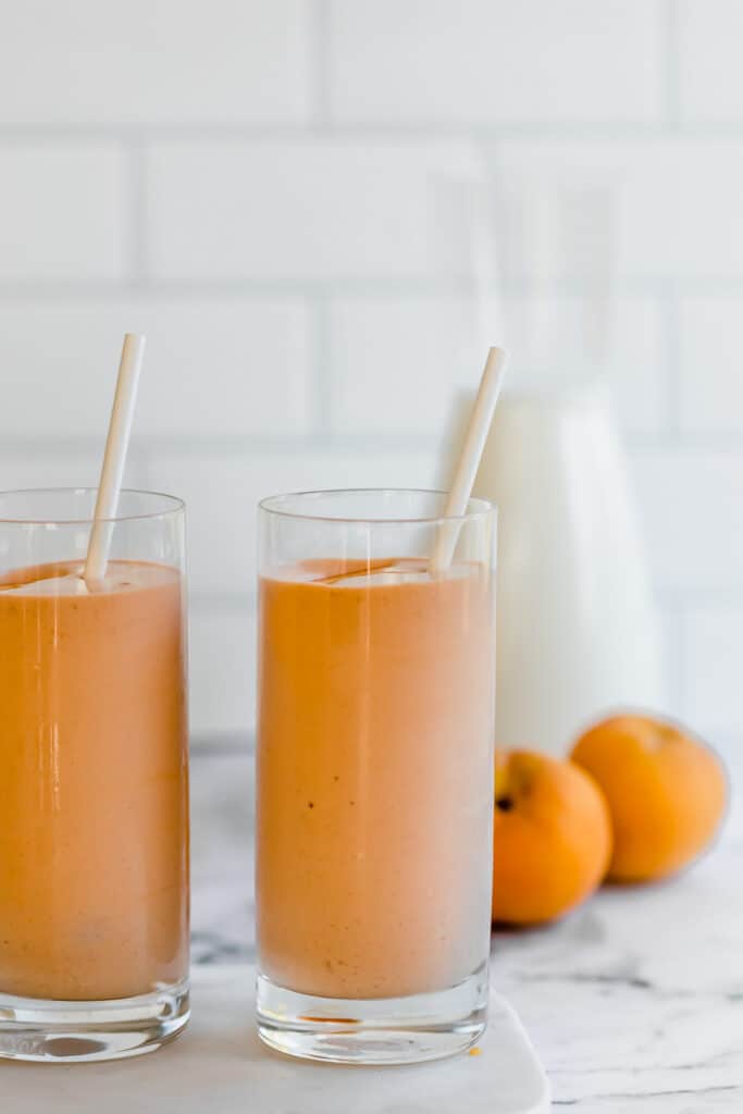 peach smoothie in tall glasses with milk jug
