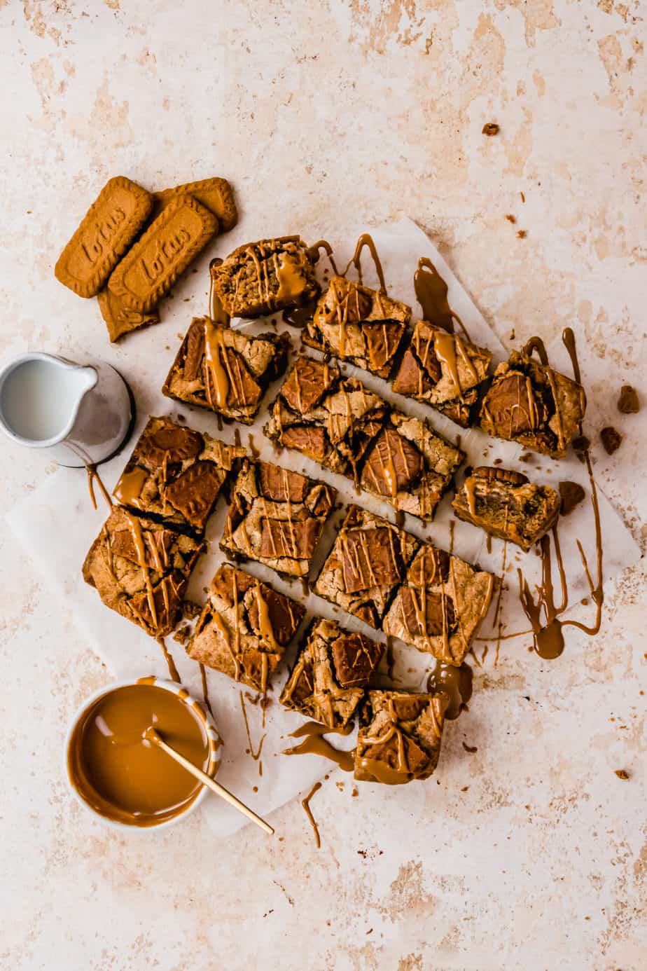 Lotus Biscoff Blondies on baking paper with drizzle of caramel sauce.