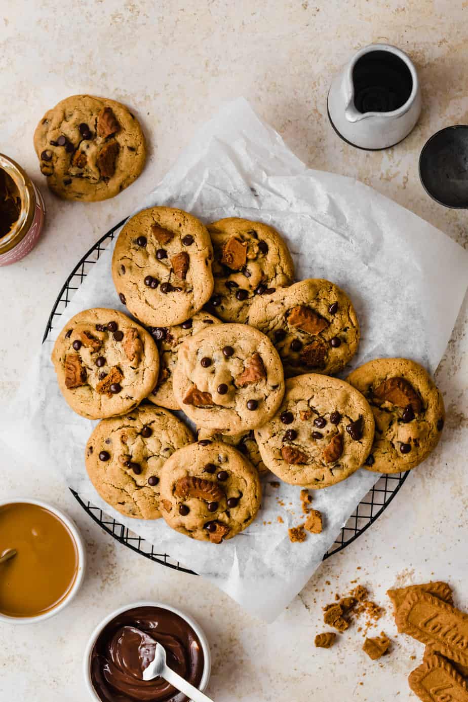 biscoff cookies on parchment paper with biscoff spread and melted chocolate