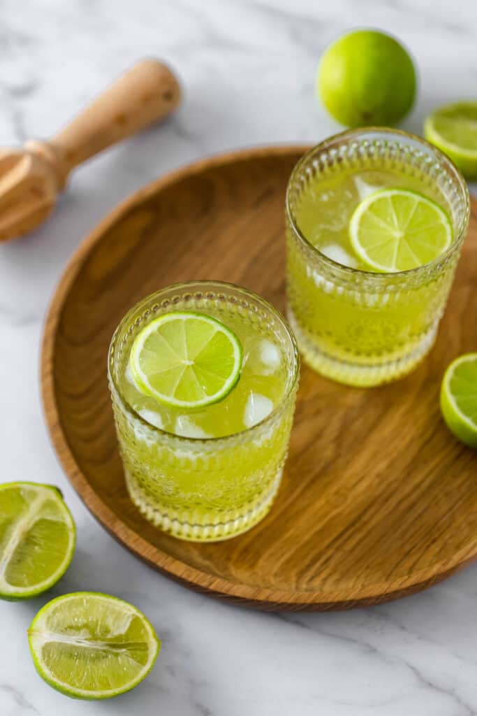 two glasses on wooden board with fresh limes
