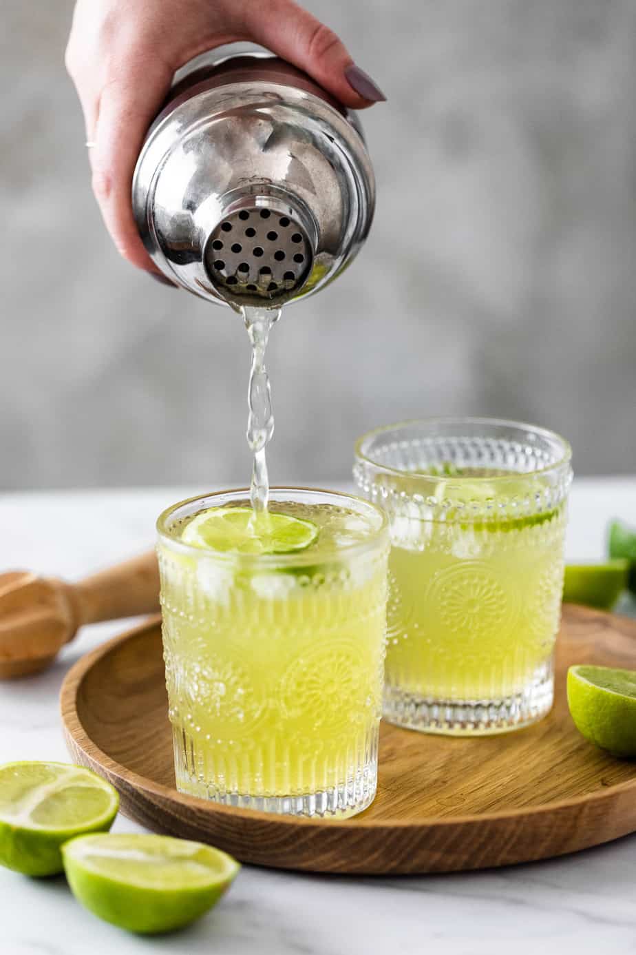 midori iced tea in two glasses on wood with silver cocktail shaker